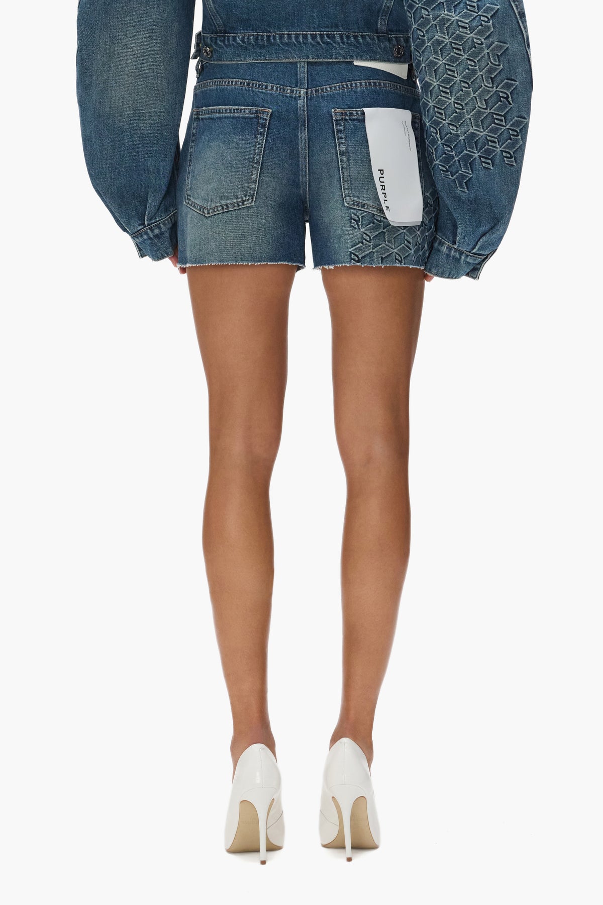 Monogram Short in Mid Indigo with embossed design, high rise, slim fit, and raw cut hem.