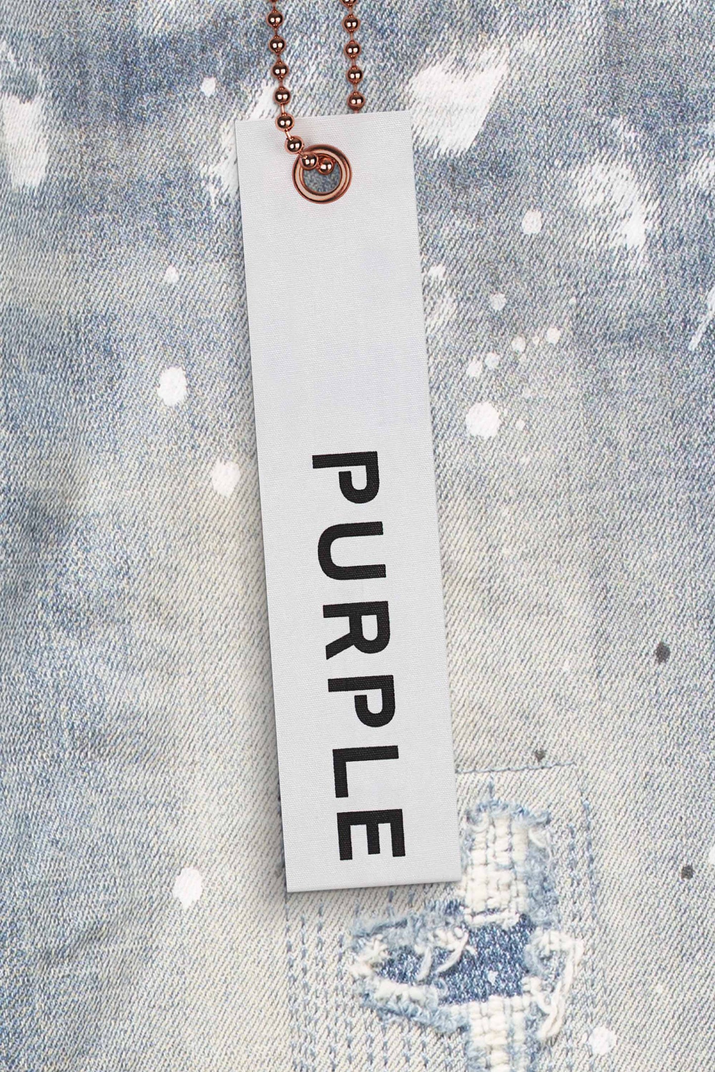 Low rise skinny jeans in light indigo wash with blowout knee detailing and paint splatter.