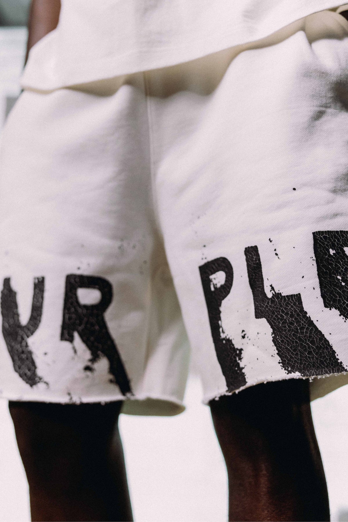 Painted Wordmark Sweatshorts in white fleece with drawcords and Purple Brand logo lettering