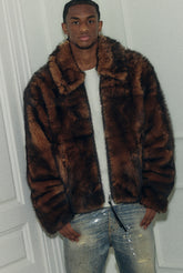 Person wearing a brown fur jacket in front of a white door.