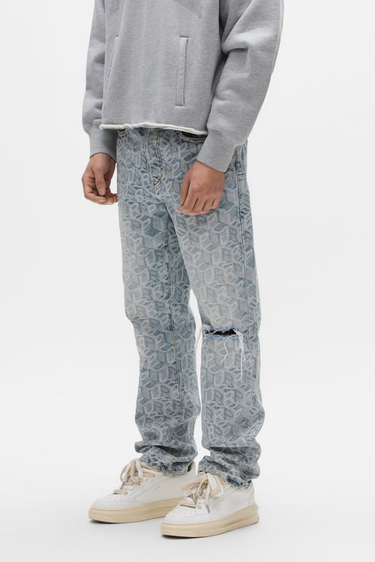 A person wears the PURPLE BRAND P011 Jacquard Monogram light grey sweatshirt, mid-rise ripped knee straight leg jeans, and white sneakers, standing against a plain white background.