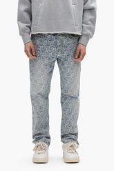 A person wears a gray sweatshirt, white sneakers, and PURPLE BRAND P011 Jacquard Monogram light blue mid-rise straight leg jeans. They stand facing forward with hands at their sides; only their body from shoulders to feet is visible.